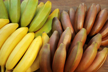 Different sorts of bananas on wooden table, closeup