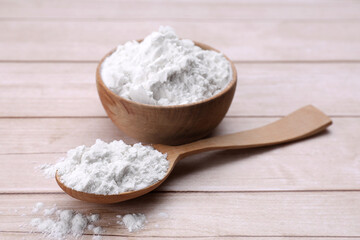 Bowl and spoon of starch on wooden table, closeup
