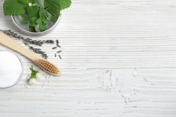 Flat lay composition with toothbrush and herbs on white wooden table. Space for text