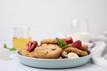 Cookies with freeze dried fruits, mint and nuts on white tiled table, closeup. Space for text