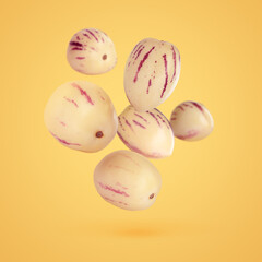 Fresh ripe pepino melons falling on pale orange background