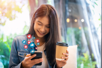 Young asian women watching live streaming video in a cafe coffee shop. Happy female using mobile...