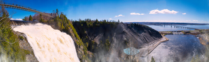 Obraz premium Montmorency Falls, or Chutes Montmorency in French, a tranquil waterfall landscape with the view of the St. Lawrence River and Ile D'Orleans in Quebec, Canada