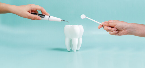 Dental treatment at the dentist. Removal of tartar. Caries treatment. White tooth on a blue background. advertising banner. Instruments for dental treatment. Mirror, toothbrush, irrigator