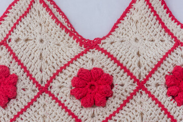 CLoseup view of the wool of a crocheted handbag with red flowers