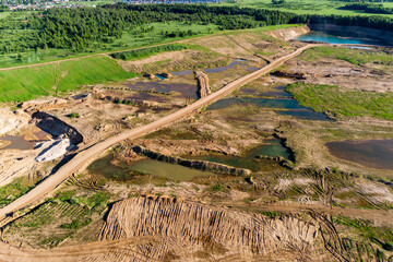 Picturesque landscape of a sand pit with a road and ponds shot from the air