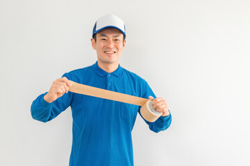 ガムテープを持つ引越し業者・配達員の男性（引越し・配達・軽貨物ドライバー・宅配・配達員・宅急便）
