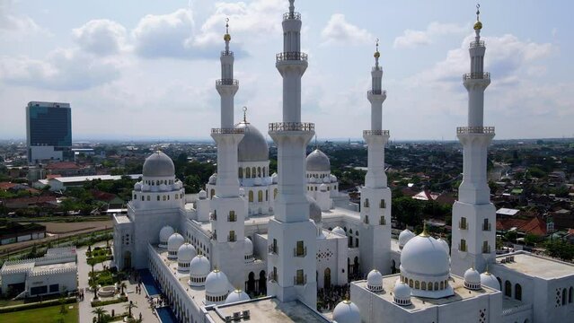 Aerial view of Sheikh Zayed Grand Mosque with cloudy sky, Solo, Central Java, Indonesia. White Mosque with cupola and minaret. Indonesian Big Mosque - 4K Drone footage