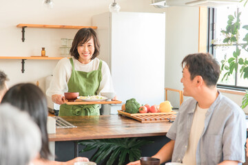 家のキッチンで家族に料理を振る舞うママ・母親・女性（ホームヘルパー・家政婦・家事代行）  © buritora