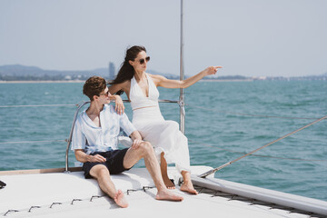 Caucasian couple who man and woman relax fun with luxury party drinking champagne by talking together while catamaran yacht boat sailing. Happy and enjoy outdoor lifestyle on summer vacation travel - obrazy, fototapety, plakaty