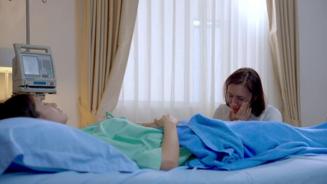 Caucasian senior mother look after her sick daughter in hospital ward. 
