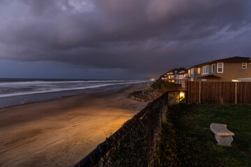 Beach houses set against dark clouds are seen just outside of Lincoln City, Oregon along the coast of the Pacific Ocean at dusk.