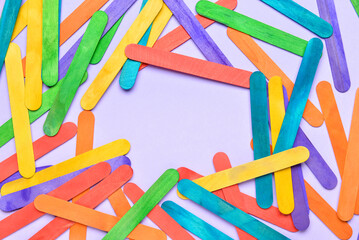 Frame made of colorful ice cream sticks on purple background