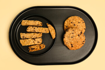Tray and plate with tasty biscotti cookies on beige background