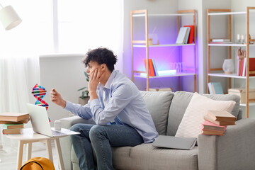 Male student studying with DNA model at home