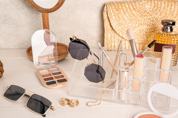 Organizer with sunglasses, makeup products, mirror and bag on white wooden table