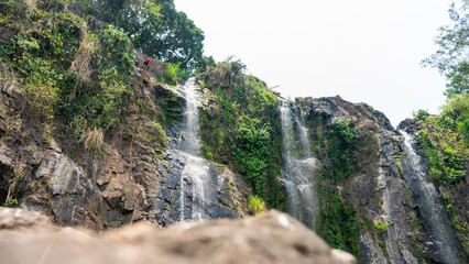 Latin man seen from afar as he descends with a rope through the rocky area of a mountain