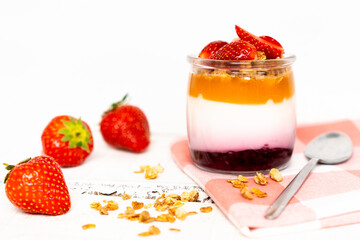 Fruit yogurt berry with muesli and fresh strawberries, on a white wooden background