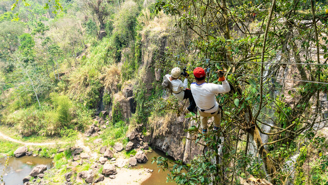 Unrecognizable Latino men throwing themselves through a canopy and recording with a video camera