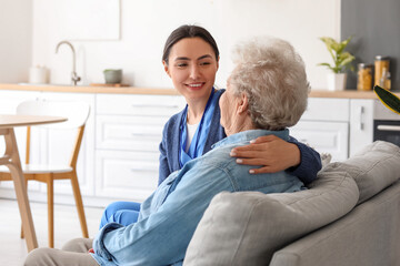 Young caregiver hugging senior woman at home