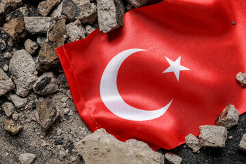 Turkish flag with stone debris on dark background. Turkey earthquake concept
