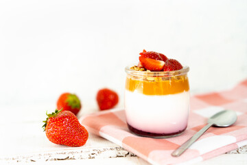 Fruit yogurt berry with muesli and fresh strawberries, on a white wooden background
