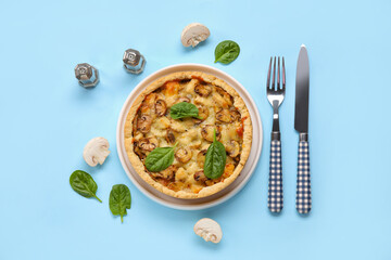 Mushroom pie with spinach leaves and cutlery on blue background