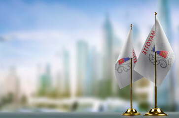 Small flags of the Mayotte on an abstract blurry background