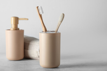 Holder of bamboo toothbrushes and bath accessories on white table