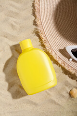 Fototapeta na wymiar Creative composition with sunscreen cream, summer hat and sunglasses on sand