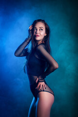 Beautiful  woman in  black  lingerie posing against a blue and pink smoke on a black isolated...
