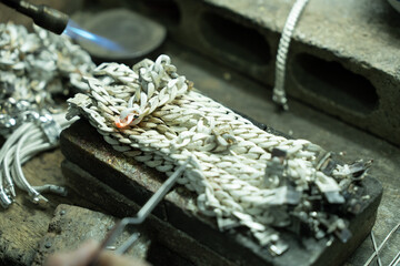 A craftsman is welding silver metal. to make a silver bracelet in local factory handmade jewelry
