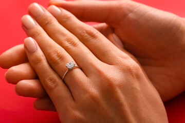 Woman with engagement ring on red background, closeup