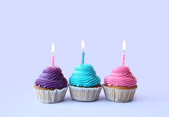 Tasty cupcakes with birthday candles on blue background