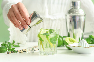 Female bartender making tasty mojito cocktail on white table