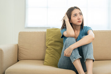 Depressed and Stressed asian woman on sofa. Crying sadness female alone in home problem in life. Unhappy asian woman headache Upset frustrated by problem love relationship feeling despair and anxiety