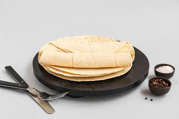 Board of thin lavash with peppercorn and salt on grey background