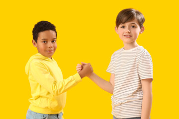 Little boys holding hands on yellow background. Children's Day celebration