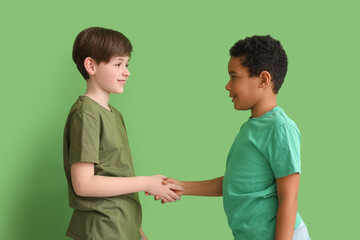 Little boys shaking hands on green background. Children's Day celebration