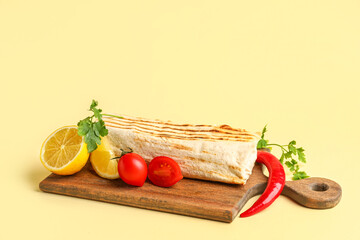 Board with tasty shawarma and ingredients on beige background