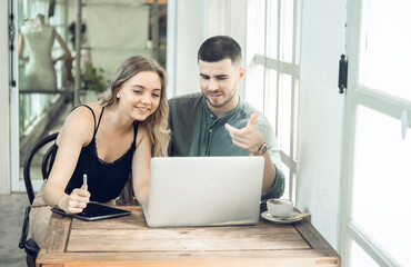 business couple Cheerful woman using laptop in coffee shop Young businessman and happy girlfriend smiling while working together Two young businessmen sit together at the table.