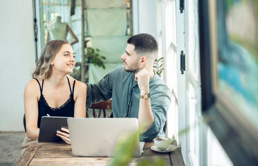 business couple Cheerful woman using laptop in coffee shop Young businessman and happy girlfriend smiling while working together Two young businessmen sit together at the table.