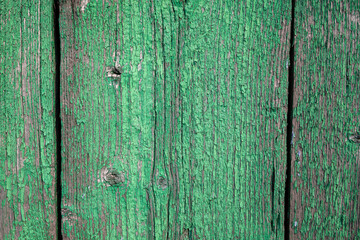 Wood texture with green flaked paint. Peeling paint on weathered wood. Old cracked paint pattern on rusty background. Chapped paint on an old wooden surface