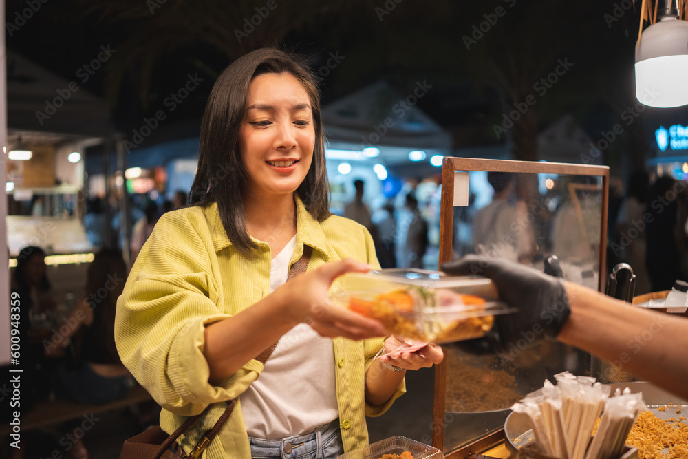 Wall mural asian woman enjoy eating noodles street food at night market. traveler asian blogger women happy tou