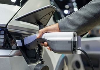 Ev car Electric car charging on parking lot. Power cable supply plugged at Electric car charging station. Eco-friendly alternative energy. Future technology battery vehicle.