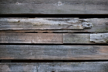 Obraz premium Weathered old wooden wall detail. Simple gray boards with knotholes and coarse grain nailed together. Outdoor. Backgrounds.