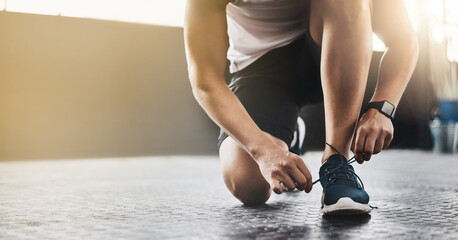 Sports, athlete and man tie shoes in a gym before workout for health, wellness and endurance...