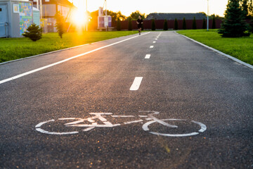 bike path with sunset sun, bicycle sign on asphalt