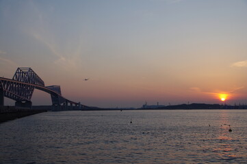 Obraz premium 夕暮れに橋の上を飛ぶ飛行機