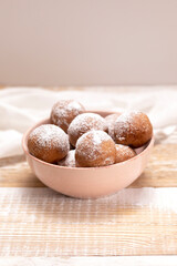 Paczki Or Zeppole In Pink Bowl With Powdered Sugar On Wooden Table. Fat Thursday Carnival or Tlusty Czwartek, Christian tradition Of Eating Doughnut, Delicious Donuts. Vertical Plane.